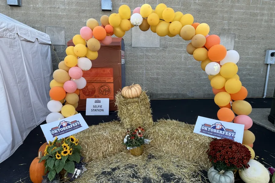 The orange and white Oktoberfest balloon arch with pumpkins and hay bales at the entrance
