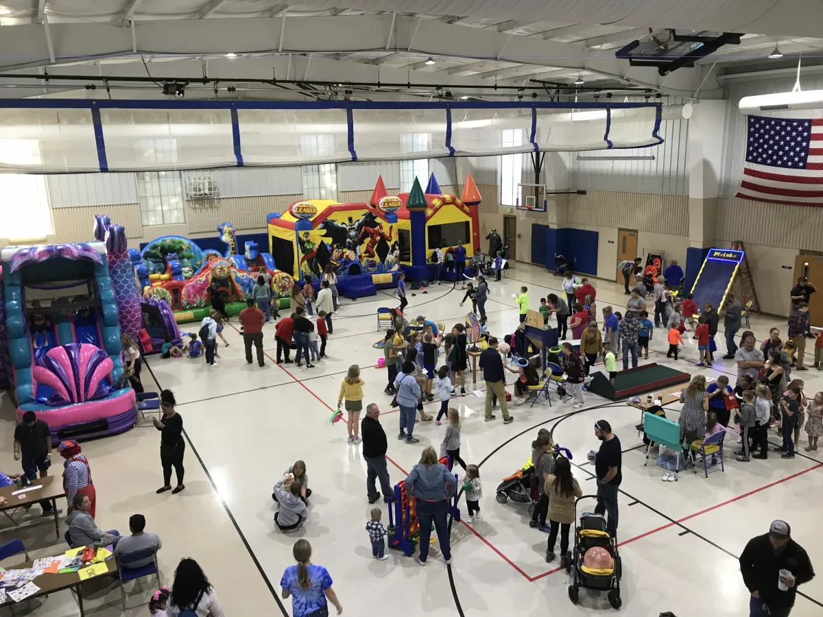 Kids and families with bounce houses in the indoor kids zone in the school gym