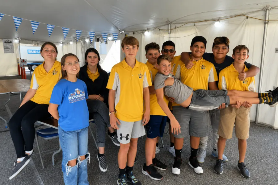 A group of Holy Name student volunteers in yellow polos having fun under the tent