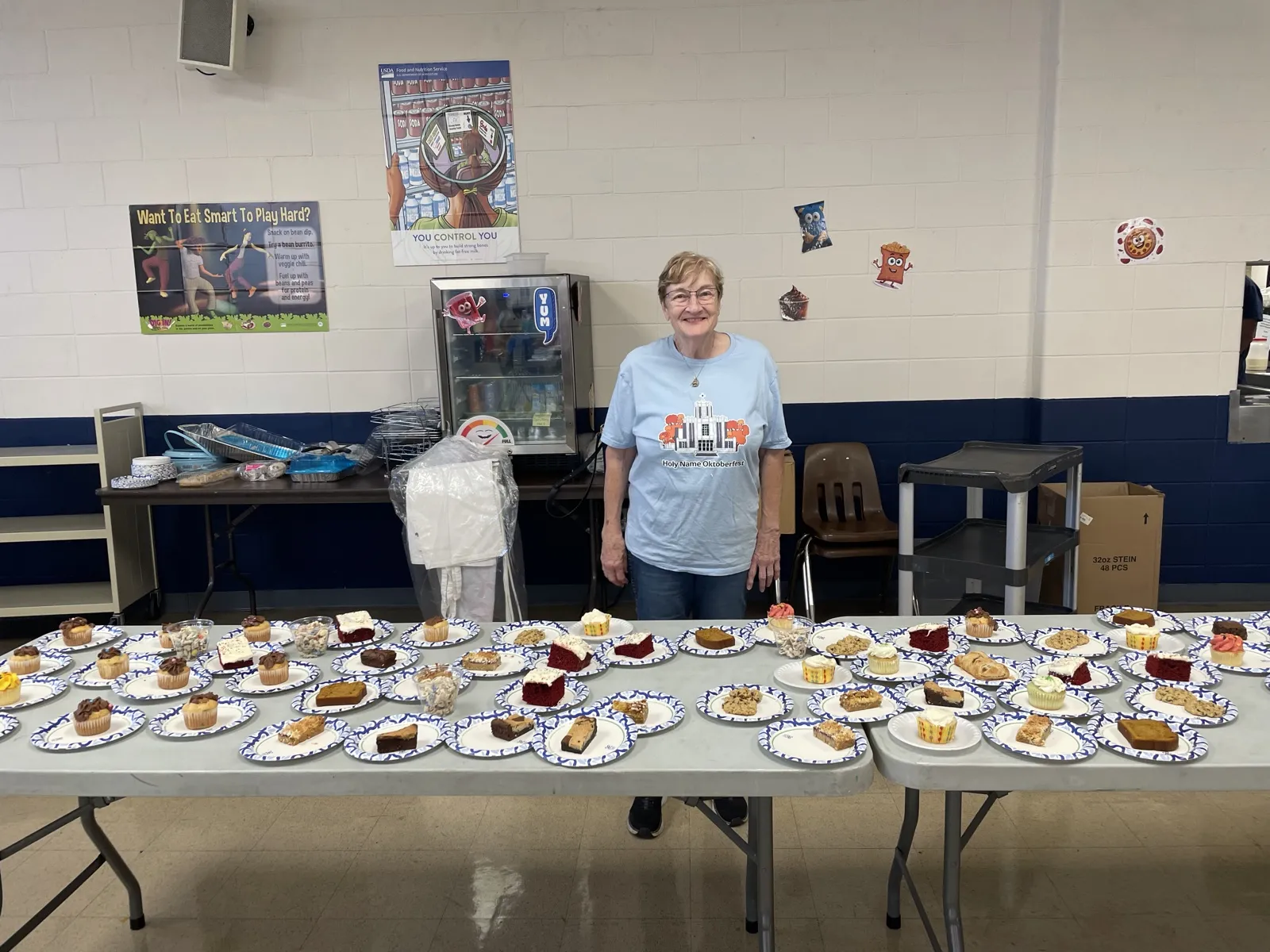 A volunteer standing behind a long table of homemade dessert plates