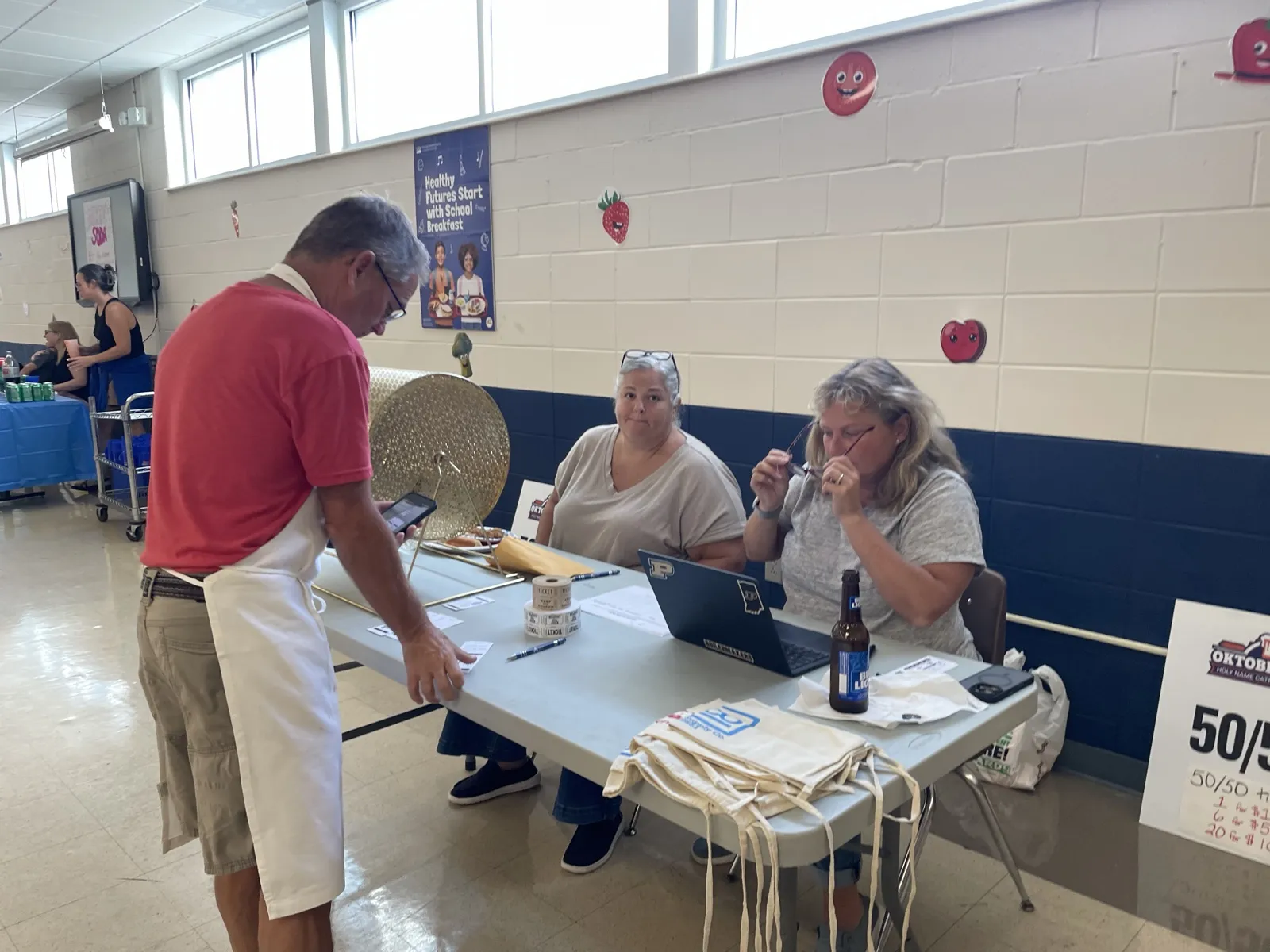 Volunteers selling raffle and 50/50 tickets at a table beside the raffle drum